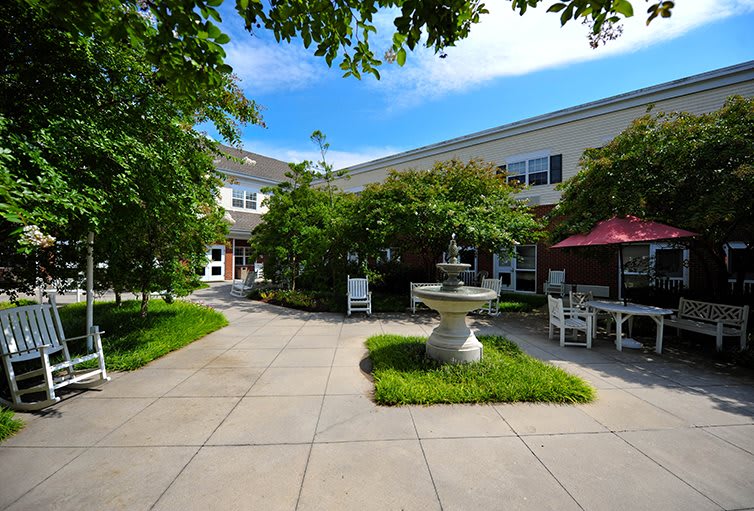 A tranquil courtyard with a central fountain, surrounded by lush greenery and seating areas.