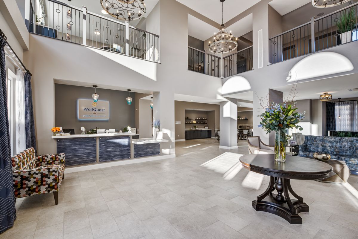 A modern and spacious lobby with chandeliers, a reception desk, and natural light.