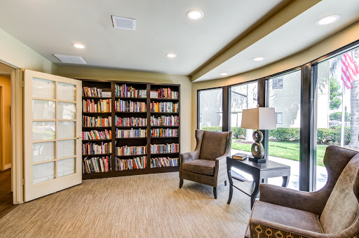A cozy reading nook featuring a bookshelf filled with books, comfortable chairs, and ample natural light.