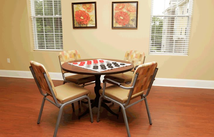A cozy room featuring a round table with four chairs and artwork on the walls.