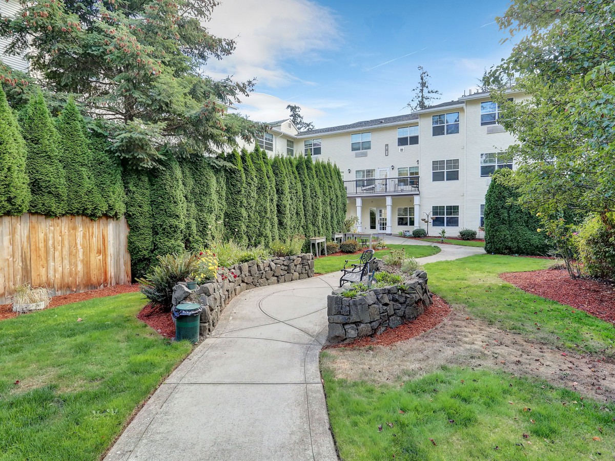 A well-maintained pathway leading through a landscaped garden to a modern apartment building.