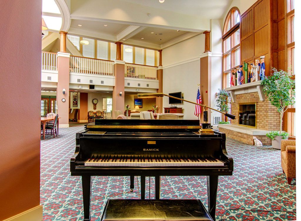 A grand piano in a spacious lobby with large windows and comfortable seating.