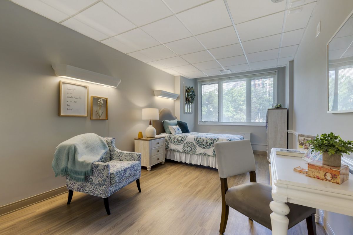 A cozy bedroom with a bed, chairs, and a window view.