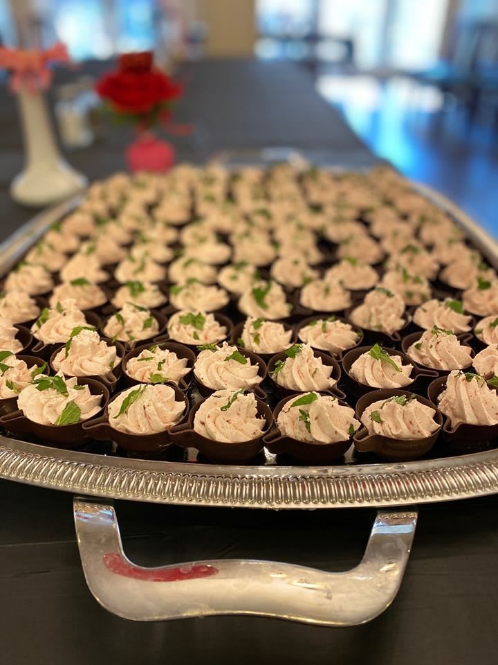 A tray filled with neatly arranged mini cupcakes, each topped with a swirl of frosting.