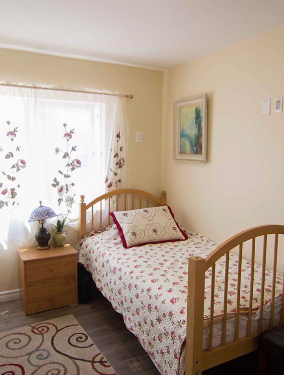 A cozy bedroom with a single bed, wooden furniture, and floral curtains.