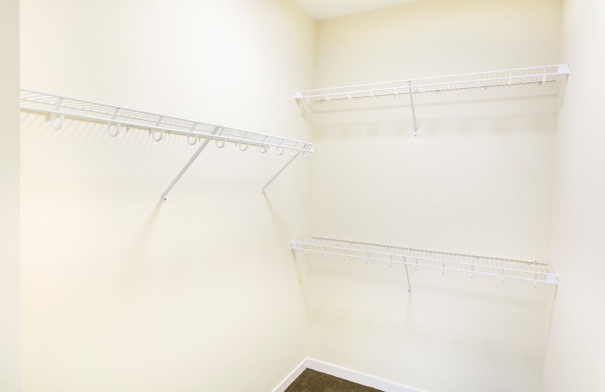 An empty walk-in closet with wire shelves along the walls.