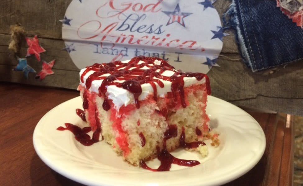 A delicious slice of cake topped with frosting and a red drizzle, served on a plate.