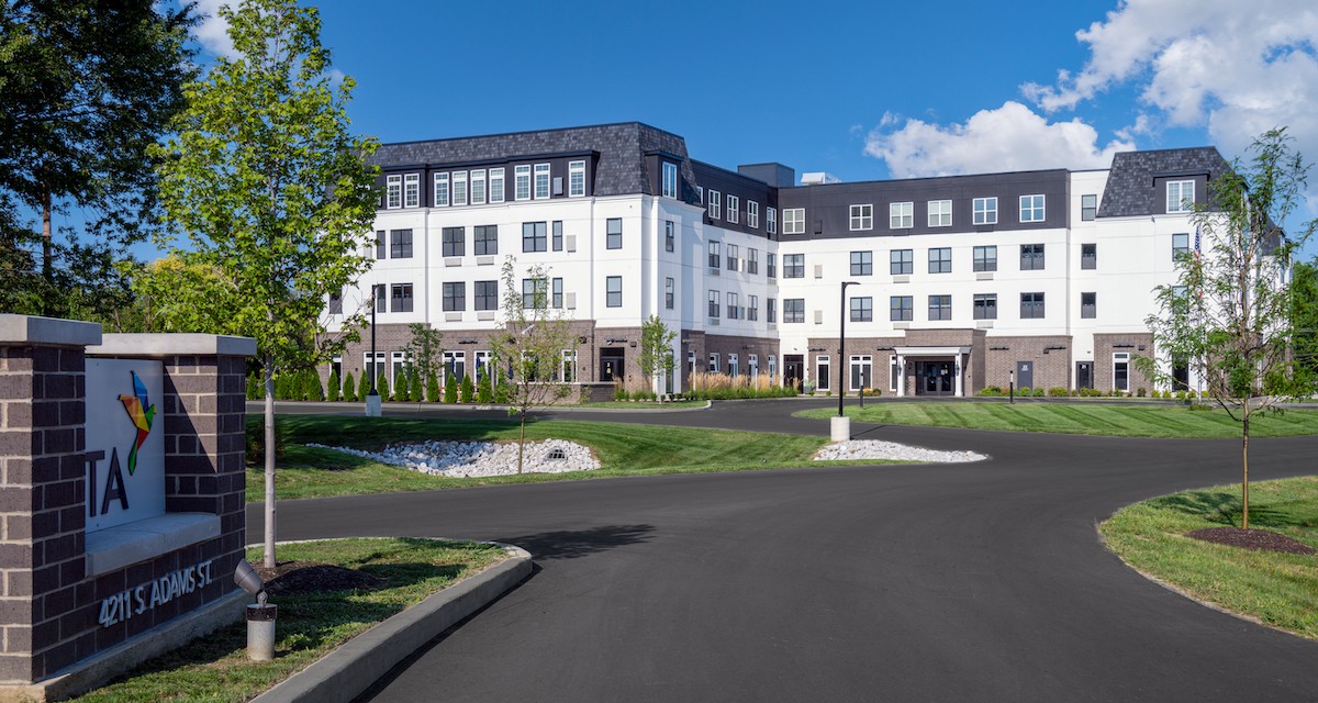 A modern residential building surrounded by well-maintained landscaping on a sunny day.