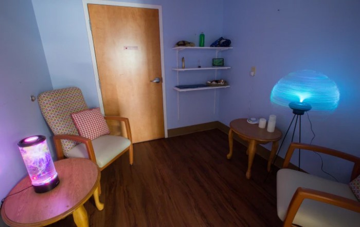 A cozy room with chairs, a table, and shelves under soft lighting.