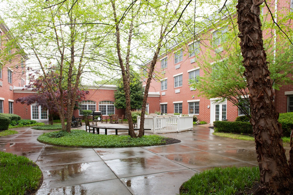 A peaceful courtyard surrounded by a brick building and lush greenery.