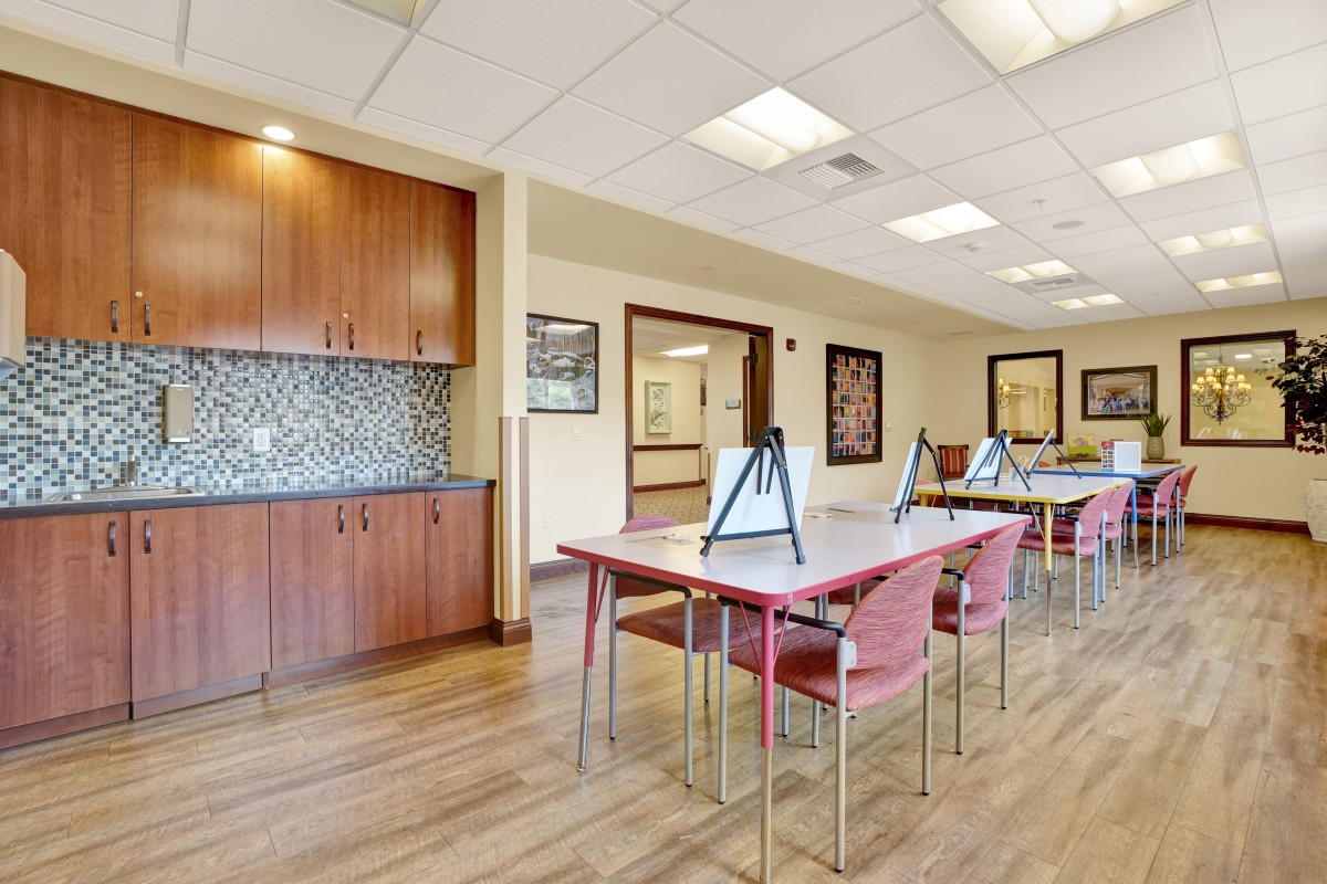 A modern interior space featuring tables and chairs with wood flooring and ample lighting.