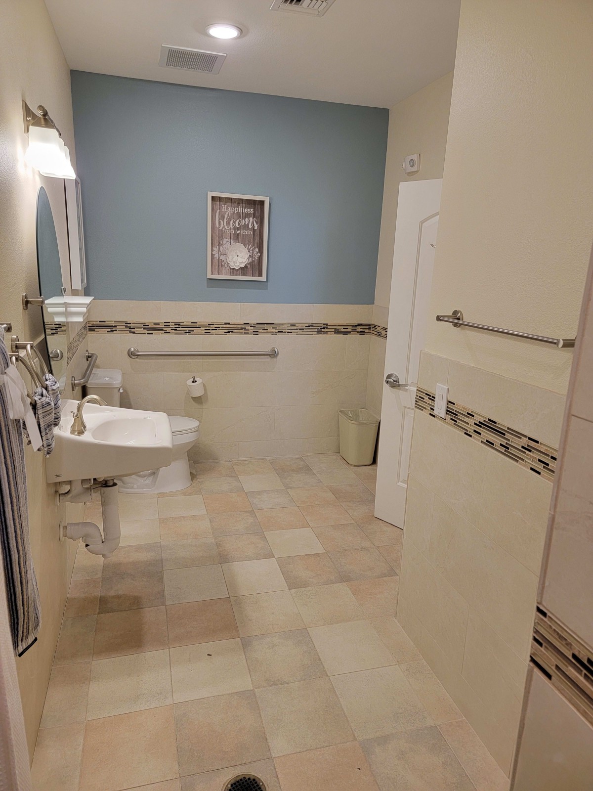 A well-lit bathroom with a sink, mirror, and tiled flooring.