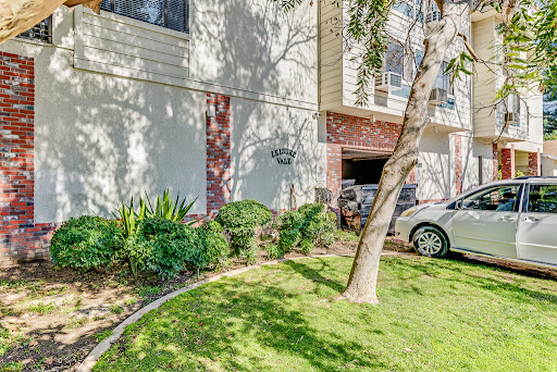 A well-maintained apartment exterior featuring landscaped greenery and parking.