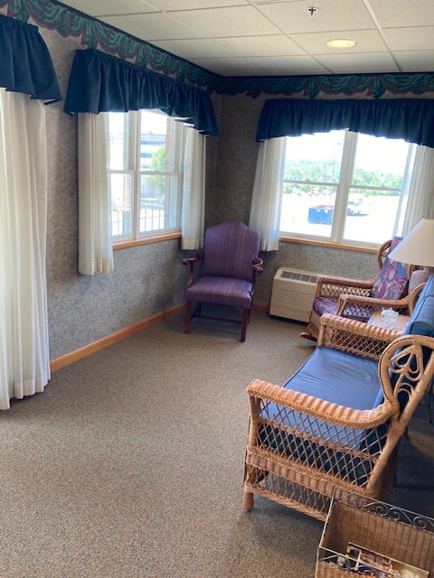 A cozy room with wicker furniture and large windows allowing natural light to fill the space.