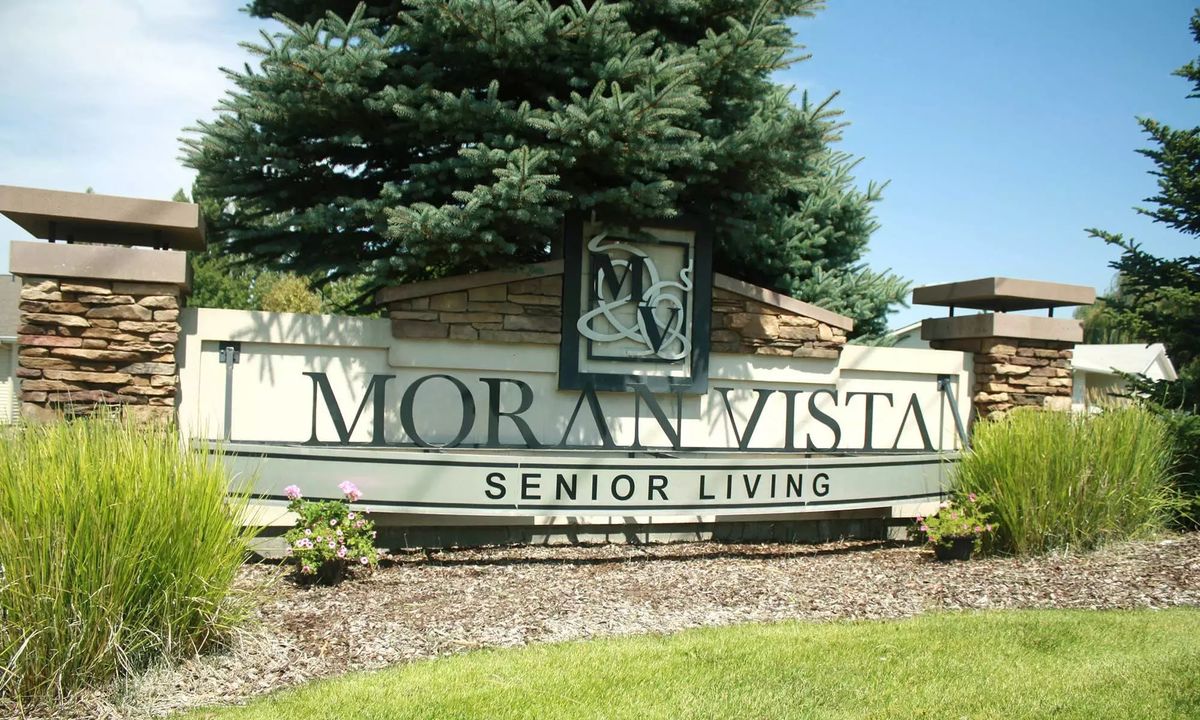 Entrance sign for Moran Vista Senior Living surrounded by greenery and trees.