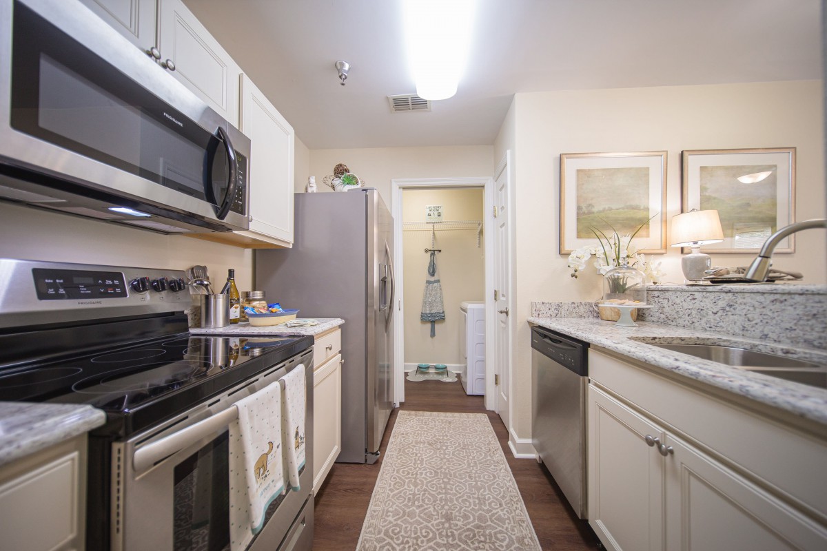 A modern kitchen featuring white cabinets and stainless steel appliances, including a microwave, oven, and refrigerator.