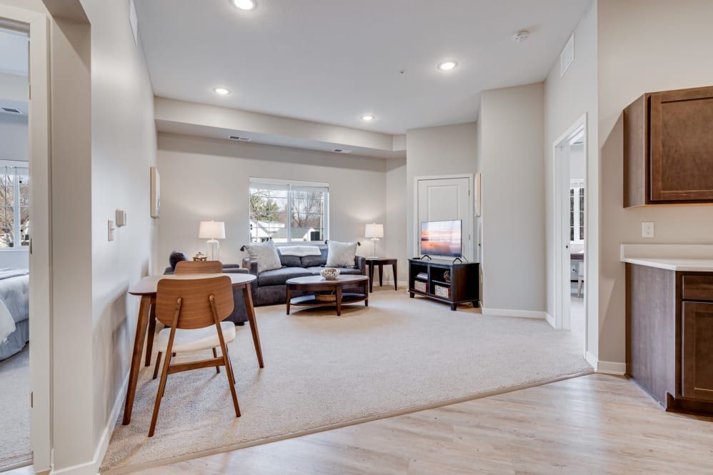 A modern and spacious living room featuring neutral colors, a comfortable sofa, wooden flooring, and a television.