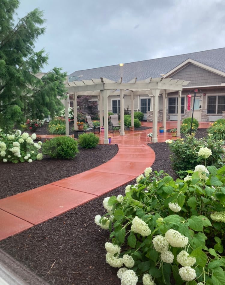 A beautifully landscaped garden with a winding pathway and pergola leads to a house.