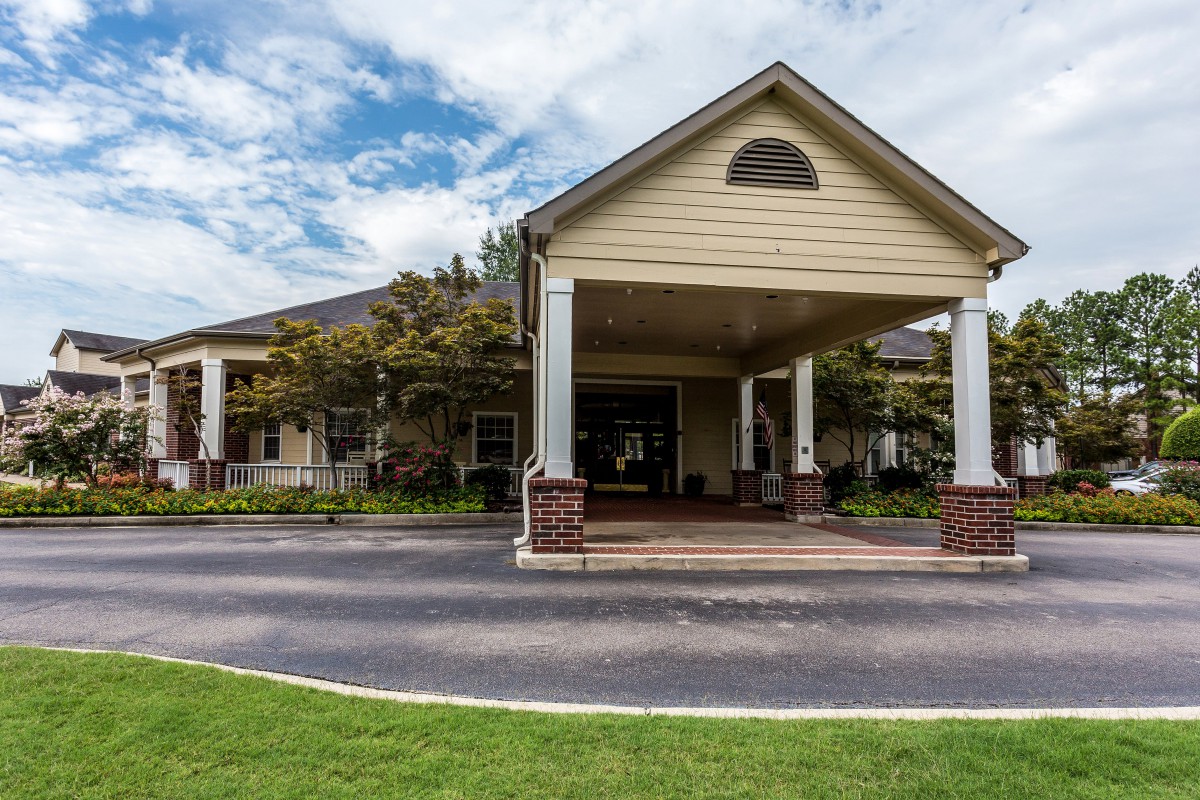 A large building with a covered entrance and landscaped surroundings.
