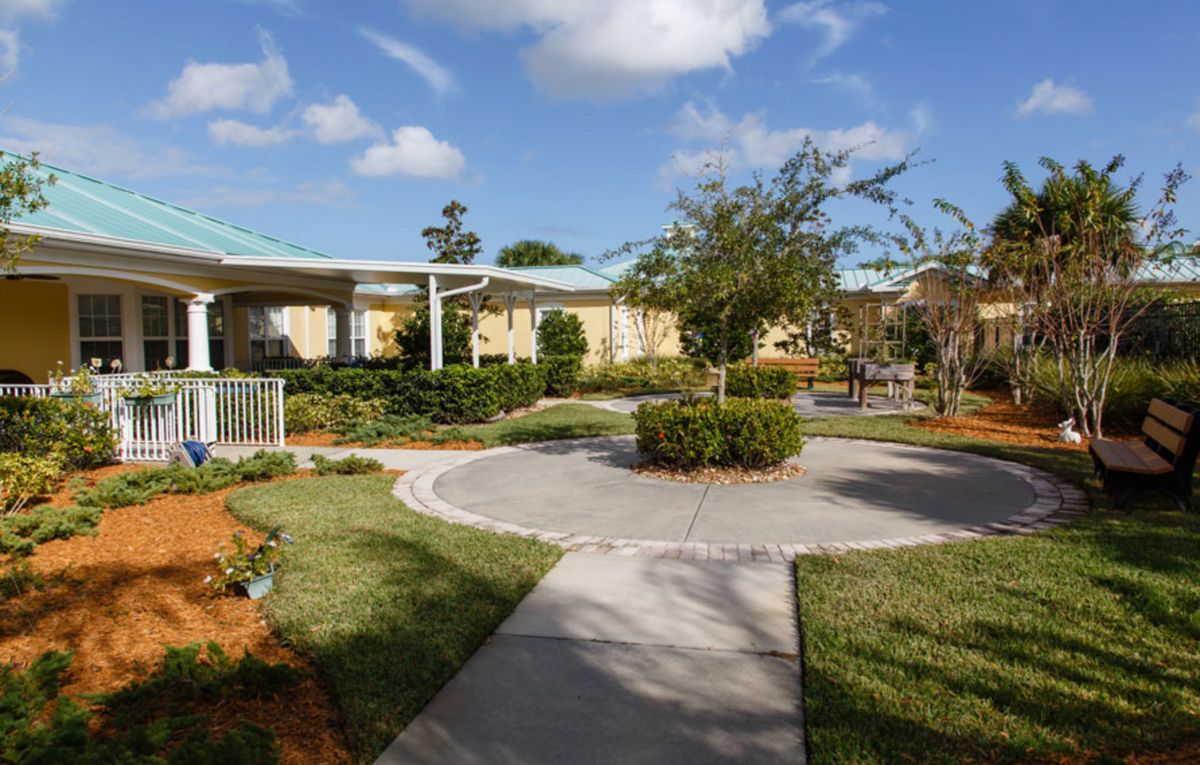 A well-maintained garden with a circular pathway and surrounding greenery under a partly cloudy sky.