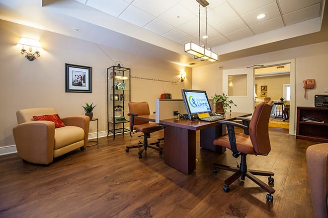 A modern office interior with a desk, chairs, and a computer setup.