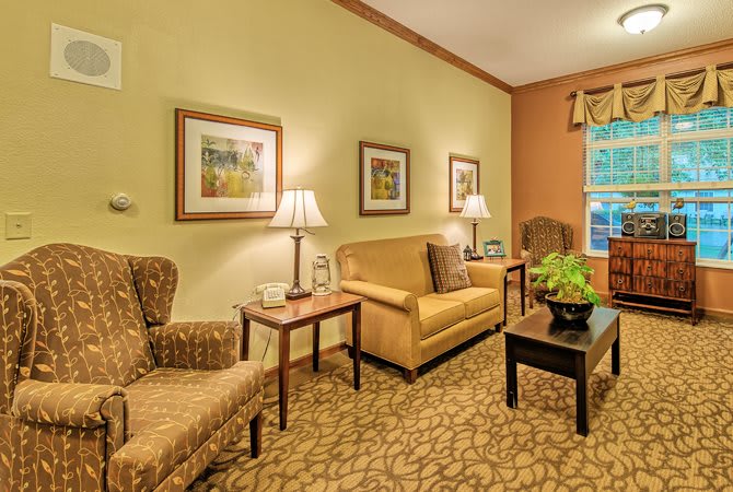 A cozy living room with a sofa, armchair, and warm lighting.