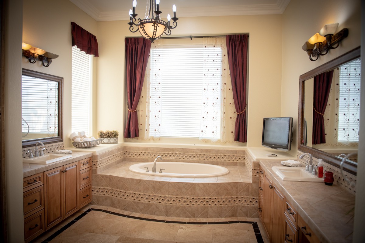 A luxurious bathroom featuring a large bathtub, elegant chandelier, and classic decor.