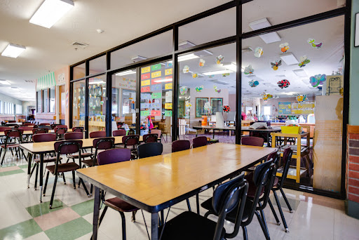 A bright and inviting classroom setup with tables and chairs arranged for group activities.