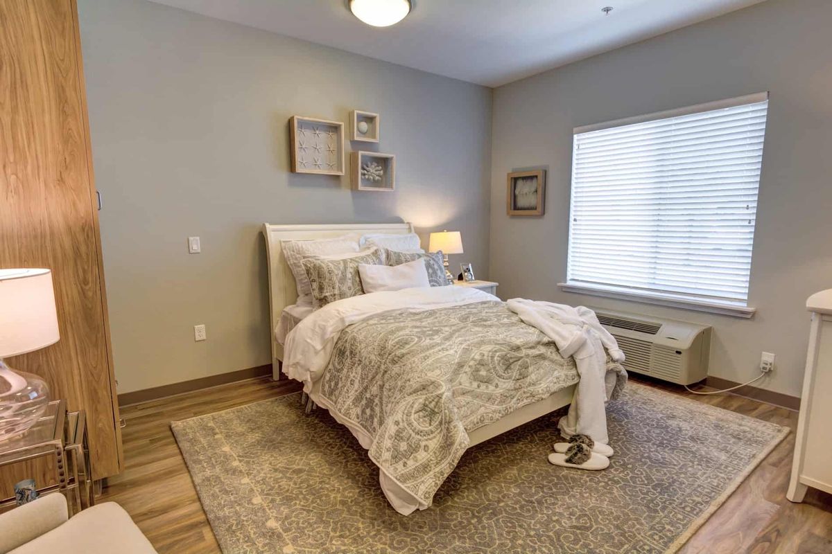 A cozy and well-designed bedroom featuring a neatly made bed, soft lighting, and neutral tones.