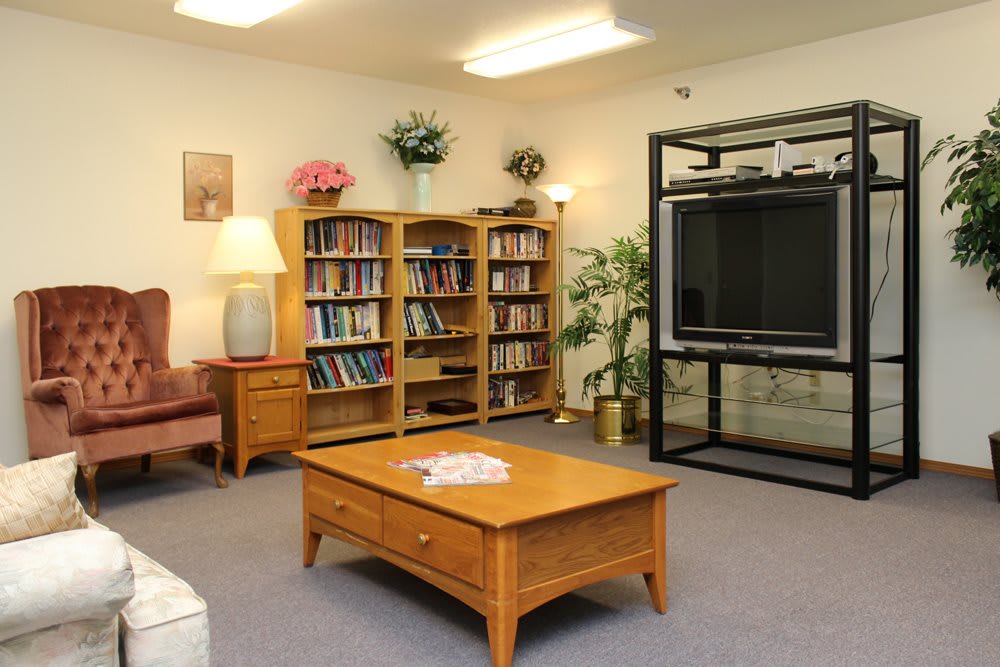 A cozy living room with bookshelves, a large TV, and a wooden coffee table.