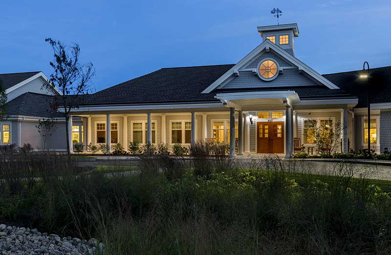 A charming house illuminated at dusk with a welcoming porch and surrounding garden.