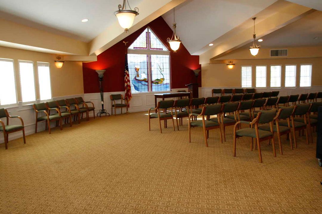 A carpeted room with arranged chairs and large windows, suitable for meetings or gatherings.