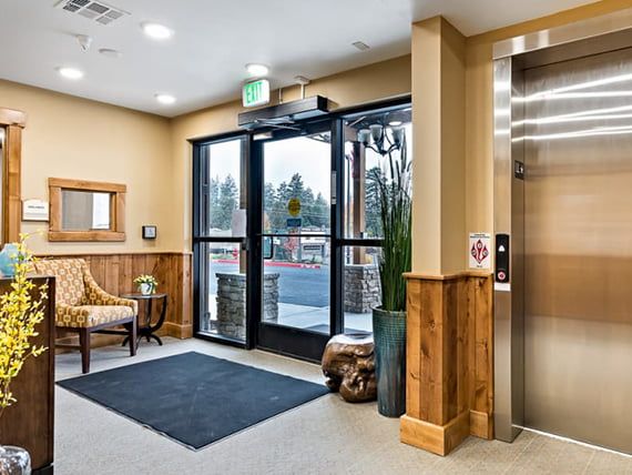A welcoming lobby with an elevator, seating area, and glass doors leading outside.