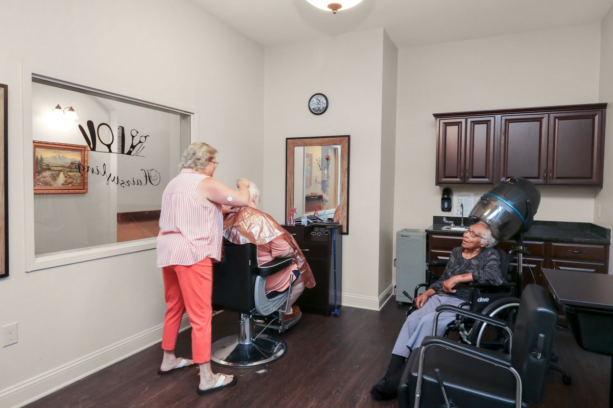 A cozy barber shop with a hairdresser attending to a customer while another person waits.