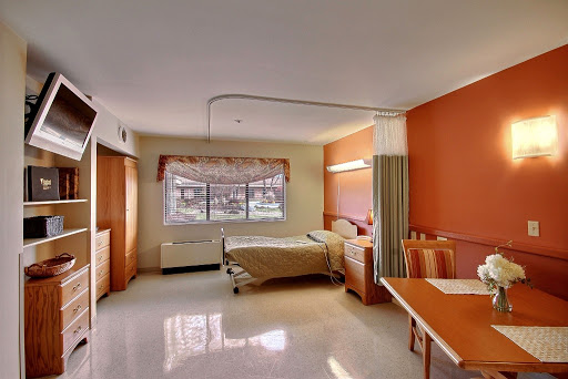 A bright and clean hospital room equipped with a bed, table, and window.