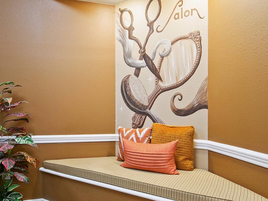 A cozy salon waiting area featuring a bench with cushions and decorative scissors artwork on the wall.