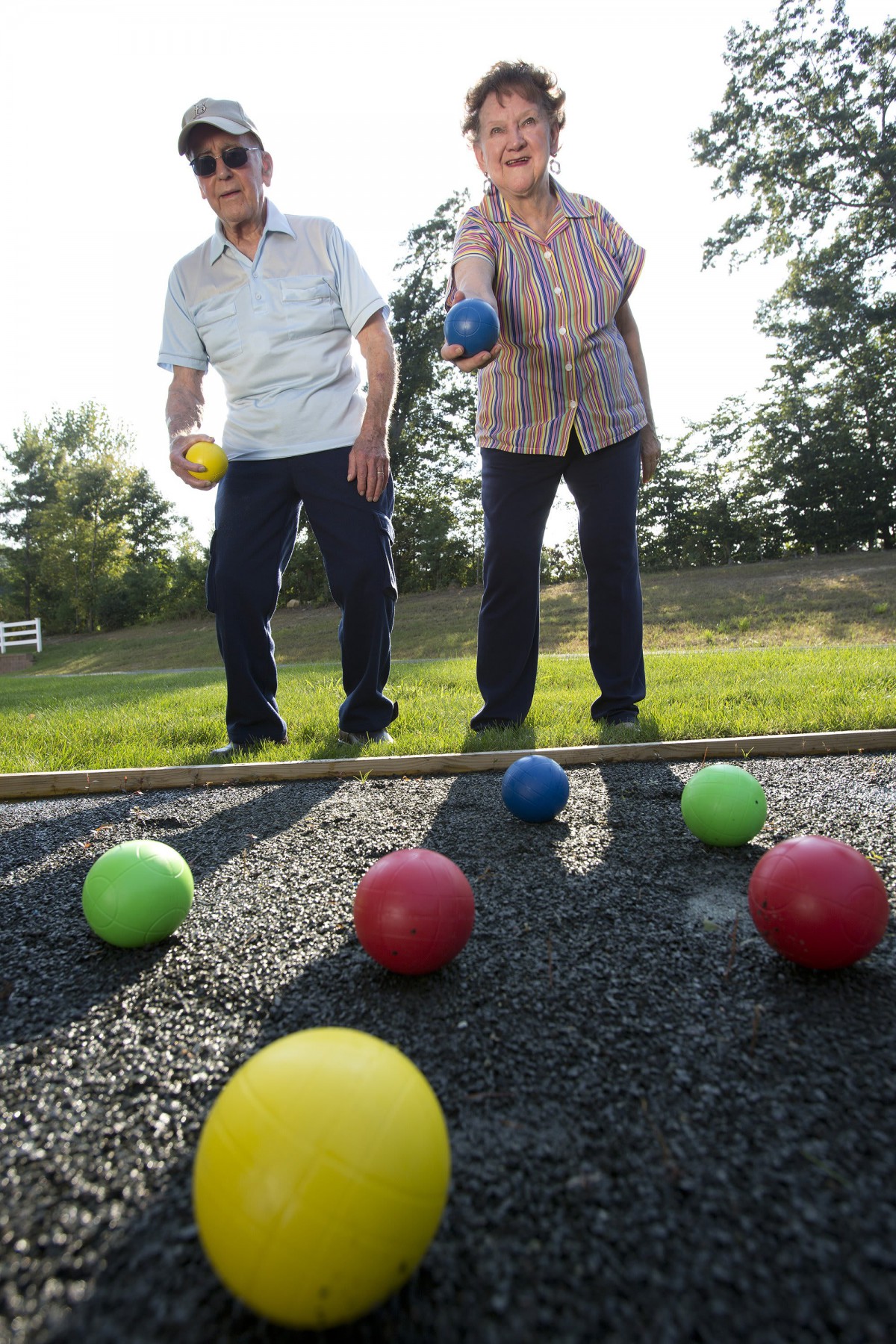 Two seniors playing bocce ball outdoors in a park.