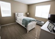 A minimalist bedroom with a single bed and neutral decor.