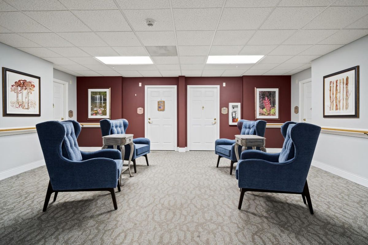 A modern lounge area with blue armchairs and framed artwork on the walls.
