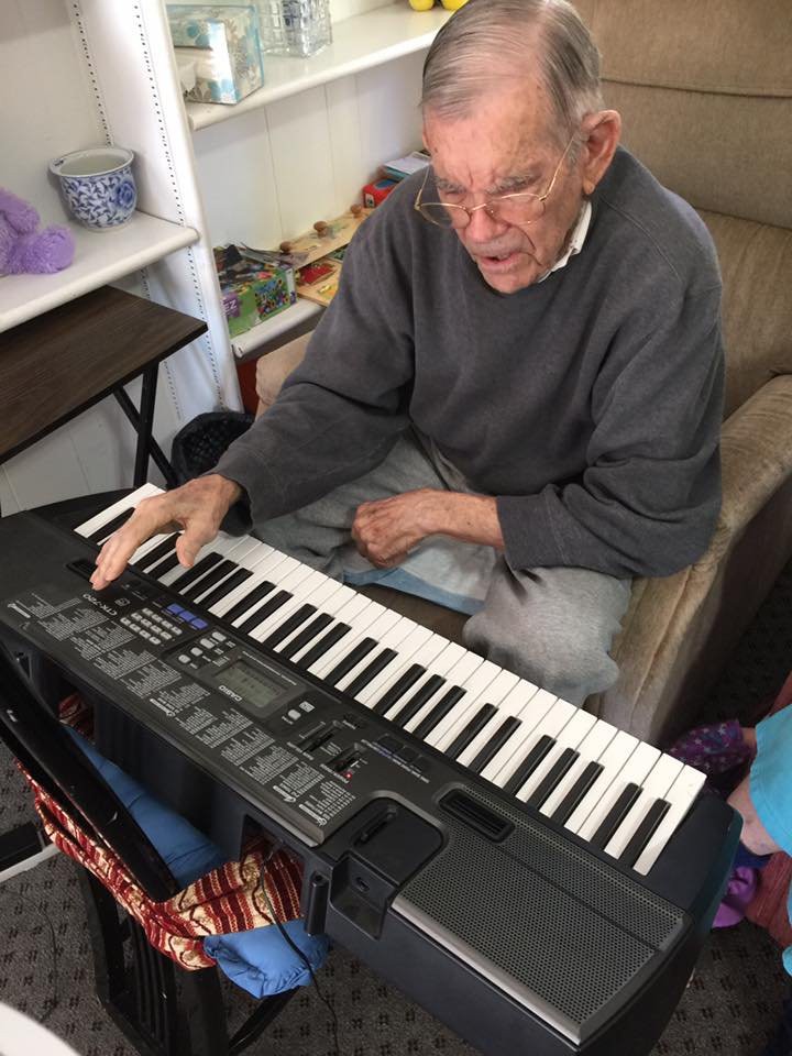 An elderly person playing a keyboard indoors.