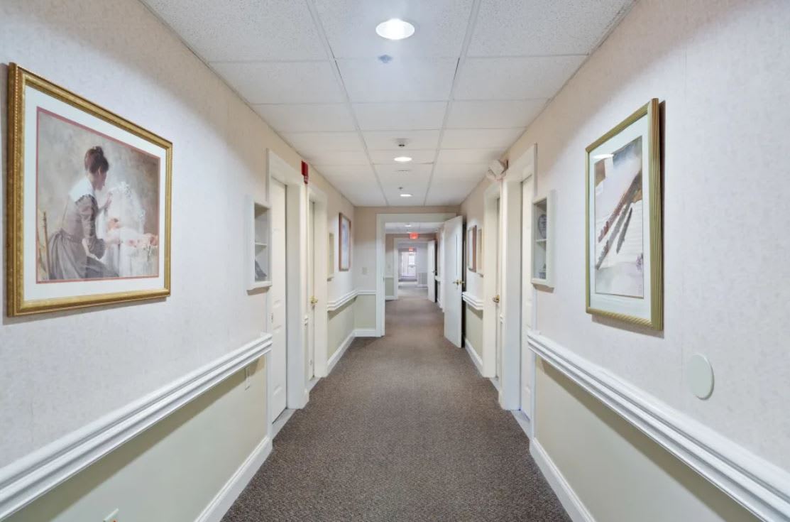 A well-lit hallway with doors and framed artwork on the walls.