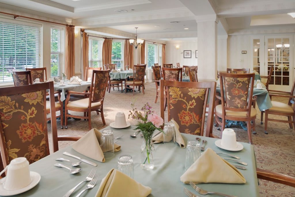 An elegantly set dining room with multiple tables and chairs, ready for guests.