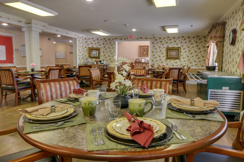 A warmly decorated dining room with a neatly set table, featuring elegant dishware and comfortable seating.