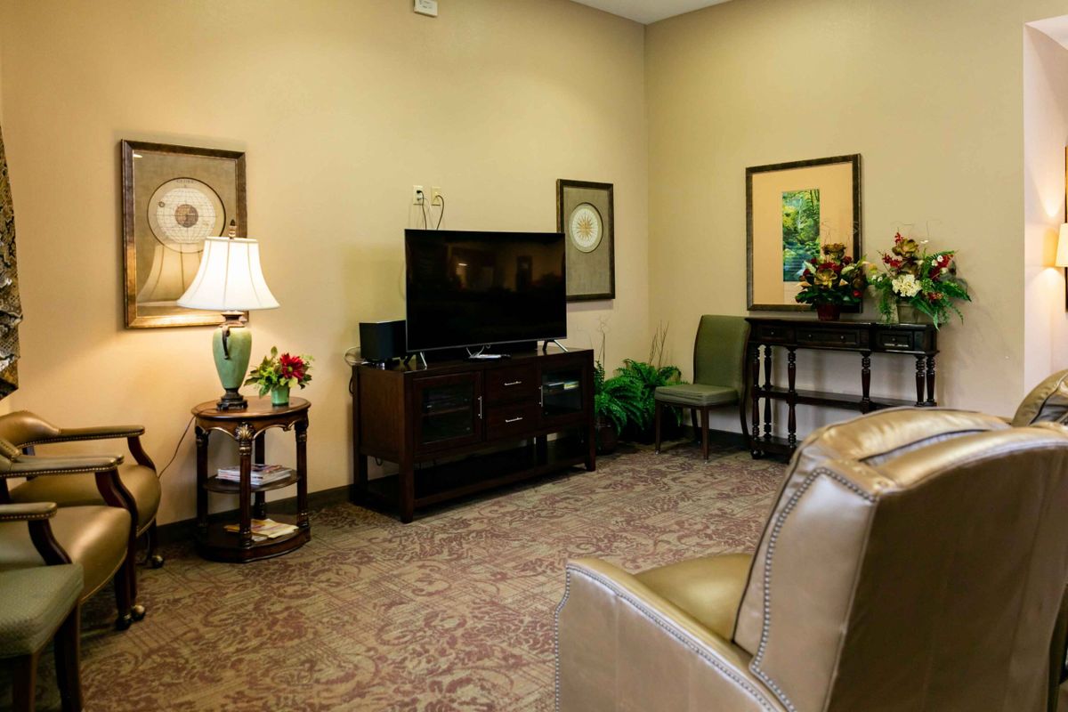 A cozy living room with a television, artwork, and comfortable seating.