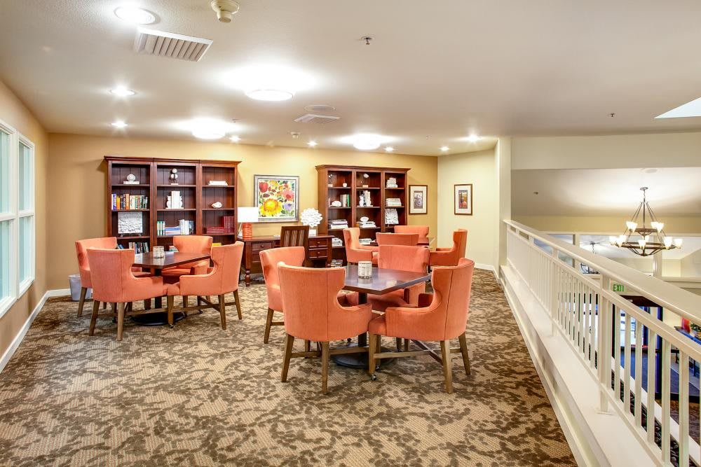 A cozy library seating area with orange chairs and bookshelves.