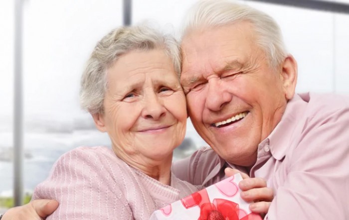 An elderly couple happily embracing with a gift.