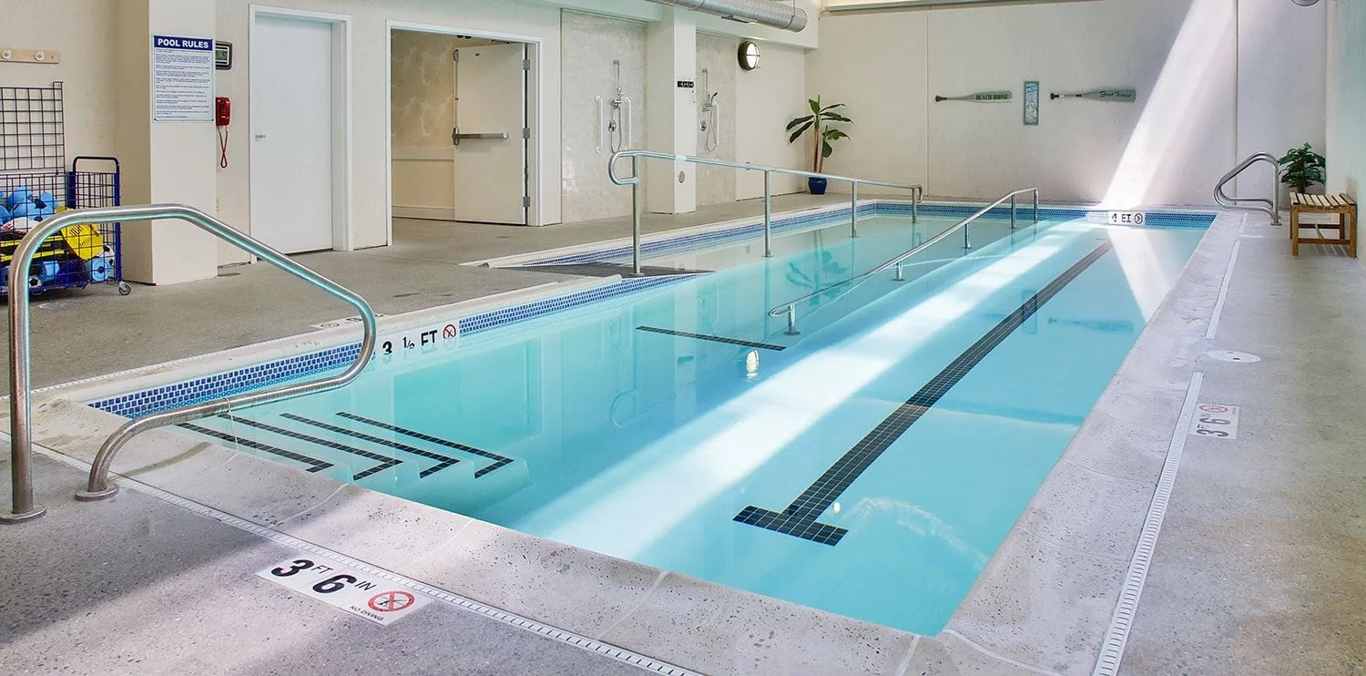 An empty indoor swimming pool with clear water and lane markings.