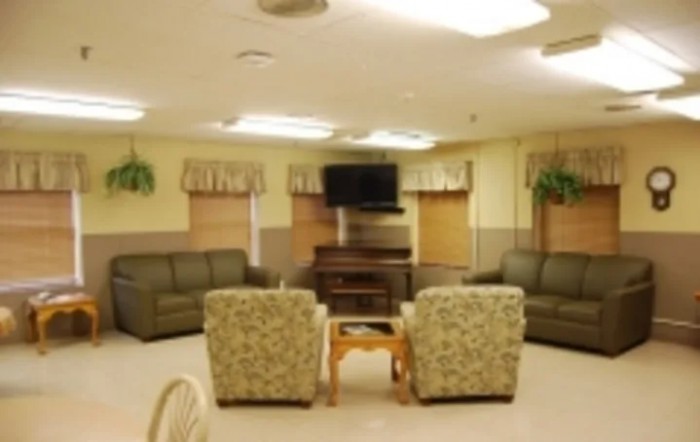 A cozy living room with sofas, armchairs, a coffee table, and a wall-mounted television.