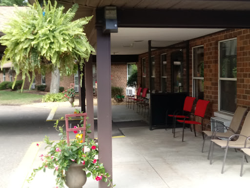 A welcoming entrance with red chairs and hanging plants, creating a cozy outdoor atmosphere.