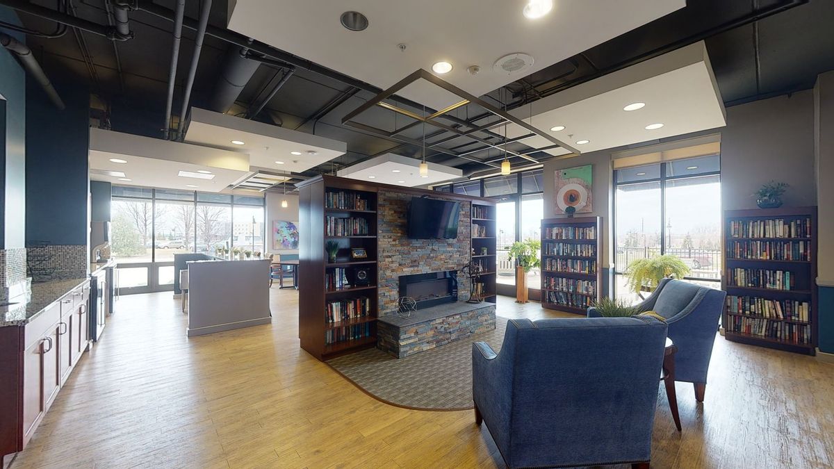 A cozy lounge area with a fireplace, bookshelves, and modern seating.